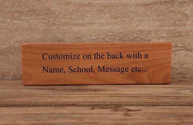 May include: A wooden sign with the text "Customize on the back with a Name, School, Message etc..." engraved on it.