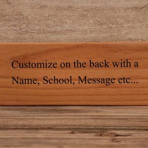 May include: A wooden sign with the text "Customize on the back with a Name, School, Message etc..." engraved on it.