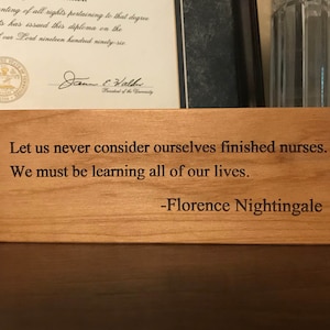 May include: A wooden plaque with a quote by Florence Nightingale: "Let us never consider ourselves finished nurses. We must be learning all of our lives."