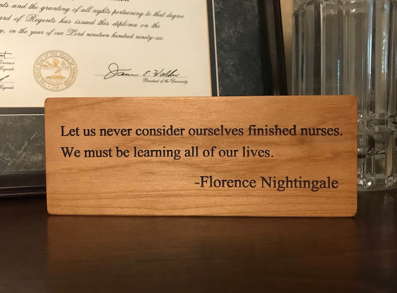 May include: A wooden plaque with a quote by Florence Nightingale: "Let us never consider ourselves finished nurses. We must be learning all of our lives."