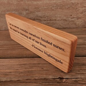 May include: Wooden plaque with a quote by Florence Nightingale: "Let us never consider ourselves finished nurses. We must be learning all of our lives."