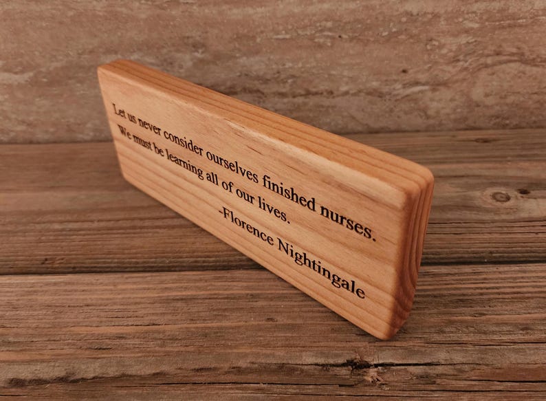 May include: Wooden plaque with a quote by Florence Nightingale: "Let us never consider ourselves finished nurses. We must be learning all of our lives."