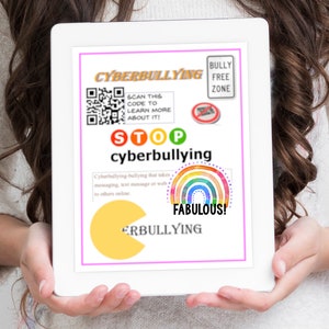 May include: A tablet screen displaying a poster with the words "Cyberbullying" and "Stop cyberbullying". The poster has a QR code, a rainbow, and a Pac-Man graphic. The text "Bully Free Zone" is in a red box at the top of the poster.