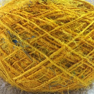 May include: A ball of yellow yarn with blue and green accents. The yarn is made of natural fibers and has a rustic, hand-spun look.