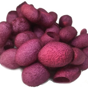 Puede incluir: Un montón de capullos de seda rosa, un material natural utilizado en artesanías y productos de belleza.
