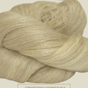 May include: A close-up of a skein of natural-colored silk yarn. The yarn is soft and delicate, and it is perfect for knitting, weaving, and crafts. The text "CREATE WITH LUXURIOUS SILK YARN" and "PERFECT FOR KNITTING, WEAVING, AND CRAFTS" is printed on a white rectangle.