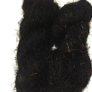 May include: Two skeins of black yarn are shown in a close-up shot. The yarn is a thick, textured wool with strands of blue, red, and gold. The yarn is tightly wound, and the overall appearance is soft and fluffy, suitable for knitting or crochet.