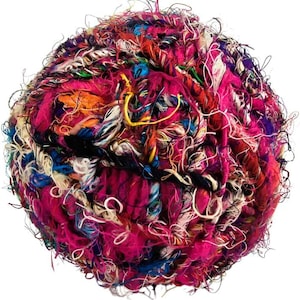 May include: A spherical ball of multi-colored yarn featuring a vibrant mix of hot pink, deep purple, bright orange, royal blue, and cream fibers. The texture is highly irregular and frayed, with loose, tangled strands creating a fuzzy appearance.