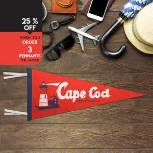 May include: A red pennant with the words "Cape Cod Massachusetts" in white script. The pennant features a lighthouse illustration. The image also includes travel accessories like sunglasses, a watch, and a toy airplane.