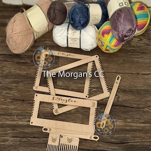 May include: A wooden loom with the name "Rhylee" engraved on it. The loom is surrounded by balls of yarn in various colors, including pink, white, brown, blue, and rainbow.