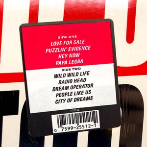 Puede incluir: Una etiqueta de disco negra y blanca con fondo rojo. La etiqueta enumera las canciones de cada lado del disco. El lado uno incluye las canciones "Love for Sale", "Puzzlin' Evidence", "Hey Now" y "Papa Legba". El lado dos incluye las canciones "Wild Wild Life", "Radio Head", "Dream Operator", "People Like Us" y "City of Dreams". La etiqueta tambi&eacute;n incluye un c&oacute;digo de barras y el n&uacute;mero 1-25512.