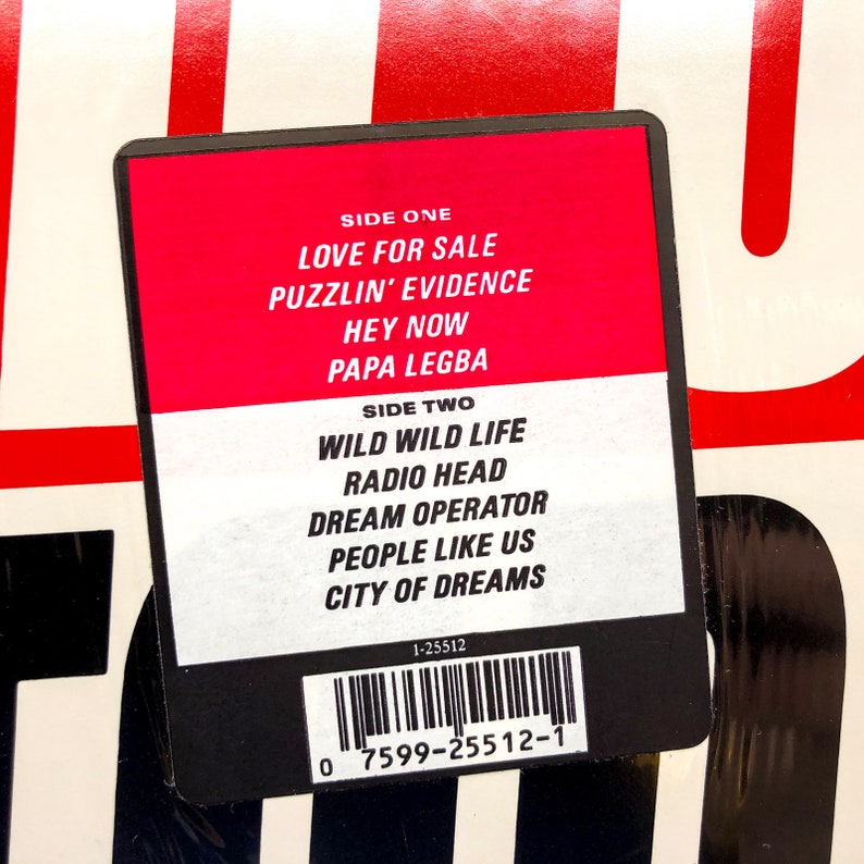Puede incluir: Una etiqueta de disco negra y blanca con fondo rojo. La etiqueta enumera las canciones de cada lado del disco. El lado uno incluye las canciones "Love for Sale", "Puzzlin' Evidence", "Hey Now" y "Papa Legba". El lado dos incluye las canciones "Wild Wild Life", "Radio Head", "Dream Operator", "People Like Us" y "City of Dreams". La etiqueta tambi&eacute;n incluye un c&oacute;digo de barras y el n&uacute;mero 1-25512.