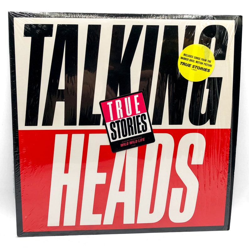Puede incluir: Una portada de &aacute;lbum de vinilo negro y rojo con el texto "Talking Heads" en letras blancas. El &aacute;lbum se titula "True Stories" e incluye canciones de la pel&iacute;cula de Warner Bros. "True Stories".