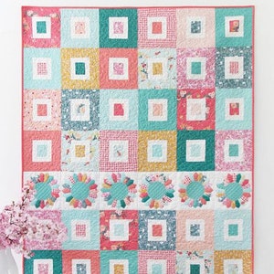 May include: A colorful quilt with a patchwork design featuring squares in shades of pink, teal, yellow, and white. The quilt has a floral pattern and is labeled "Sugar Dish" with the text "A Jelly Roll Friendly Quilt in 3 Sizes."