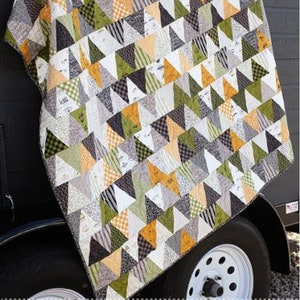 May include: A quilt pattern called "The Pines" from the "Timmer" fabric collection by "Sweetwater". The quilt is made of green, yellow, white, and black triangles. The quilt is 60 inches by 64 inches.