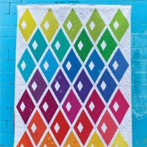 May include: A quilt pattern called "Diamond Alley" by Sassafras Lane Designs. The pattern features a white background with a series of colorful diamond shapes arranged in a diagonal pattern. The diamonds are in shades of yellow, green, blue, purple, red, and orange.
