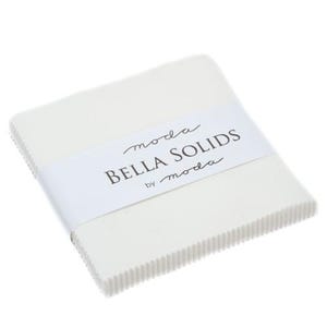 May include: A stack of white fabric squares, wrapped with a white band featuring the text "BELLA SOLIDS by moda". The edges of the fabric are textured, and the overall appearance is clean and crisp, suitable for quilting and crafting projects.