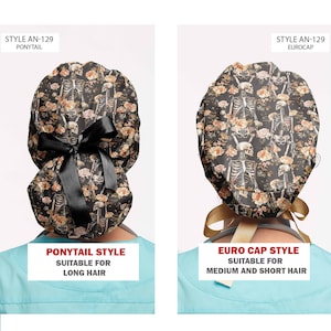 Op de afbeelding: Twee operatiemutsen met een skelet- en bloemenprint op een zwarte achtergrond. De linker muts is een paardenstaartmodel met een zwart lint, gelabeld STYLE AN-129 PONYTAIL. De rechter muts is een eurocap-model met een goudkleurig lint, gelabeld STYLE AN-129 EUROCAP.