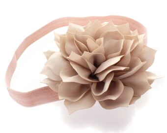May include: A light pink elastic headband with a large, beige fabric flower attached.