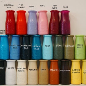 May include: A collection of 30 small glass bottles, each painted a different colour. The bottles are arranged in rows, with the colours transitioning from red to green to blue. The bottles are labelled with names such as "Colonial Red", "Fire Orange", "Lilac", "Pink", "Red Wine", "Plum", "Oasis Blue", "Cinnamon", "Wildflower Blue", "Midnight Blue", "Lagoon Blue", "Aqua", "Olive", "Oregano", "Green Apple", "Eden Green", "Grey", "Black", "White", "Heirloom White", "Almond", "Sand", "Caramel", "Espresso", "Summer Squash", "Lemon Grass", and "Jade".