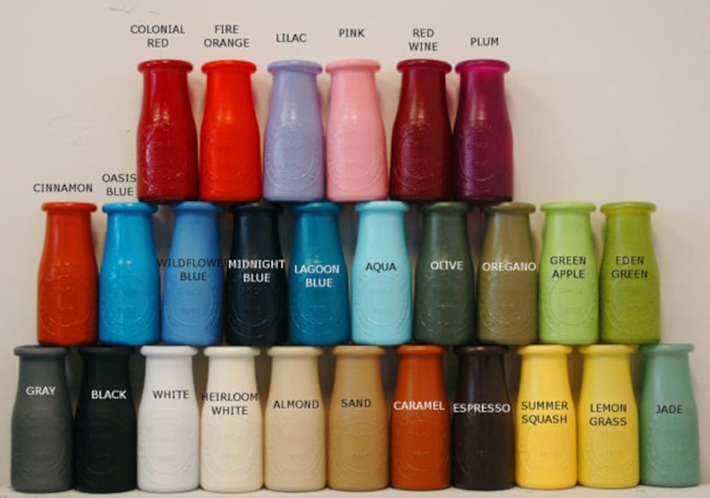 May include: A collection of 30 small glass bottles, each painted a different colour. The bottles are arranged in rows, with the colours transitioning from red to green to blue. The bottles are labelled with names such as "Colonial Red", "Fire Orange", "Lilac", "Pink", "Red Wine", "Plum", "Oasis Blue", "Cinnamon", "Wildflower Blue", "Midnight Blue", "Lagoon Blue", "Aqua", "Olive", "Oregano", "Green Apple", "Eden Green", "Grey", "Black", "White", "Heirloom White", "Almond", "Sand", "Caramel", "Espresso", "Summer Squash", "Lemon Grass", and "Jade".