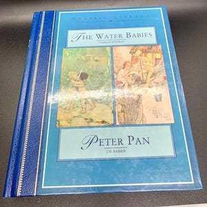 May include: A hardcover book titled "The Water Babies" by Charles Kingsley and "Peter Pan" by J.M. Barrie. The cover is light blue with gold lettering and illustrations. The spine is dark blue with gold accents.
