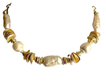 May include: A gold and white pearl necklace with gold leaf accents. The necklace is made of irregular shaped pearls and gold leaf pieces.