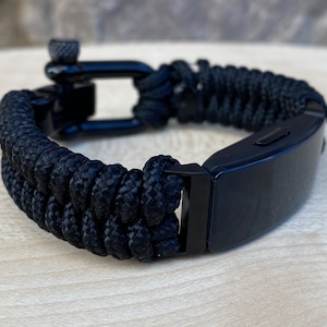 Op de afbeelding: Zwart gevlochten paracord armband met een zwarte metalen sluiting. De armband heeft een geweven ontwerp en een veilige, verstelbare sluiting. Een stijlvol accessoire voor dagelijks gebruik.