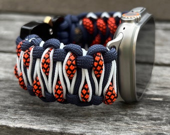 May include: A navy blue, white, and orange woven watch band with a silver Apple Watch.