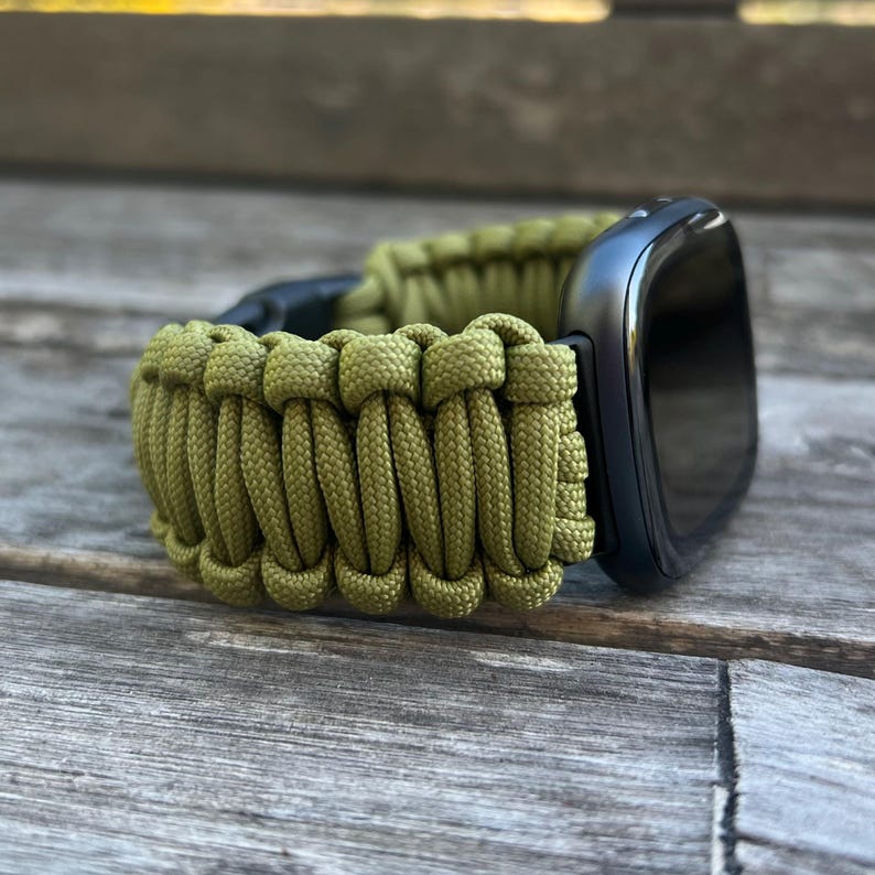 May include: A green paracord watch band with a black watch face.