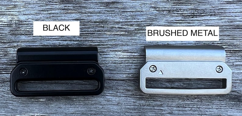 May include: Two metal belt buckle options: one black and one brushed metal. Both buckles have a rectangular shape with a cut-out in the center.