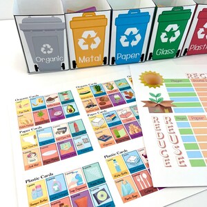 May include: A colorful set of four mini recycling bins with labels for organic, metal, paper, glass, and plastic. The bins are part of a recycling game with cards showing different items to sort. The game also includes a score sheet with the words "Reduce, Reuse, Recycle".