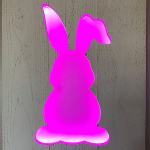 Väggdisplay med utskuren påskhare i träpall, bakgrundsbelyst och rosa LED-bandbelysning