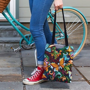 May include: A colorful tote bag with a butterfly design. The bag is made of canvas and has black handles. The bag is being held by a person wearing blue jeans and red sneakers.