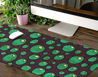 May include: A green and purple mouse pad with a repeating pattern of green circles with yellow centers. The mouse pad is on a wooden desk with a computer monitor and a potted plant.