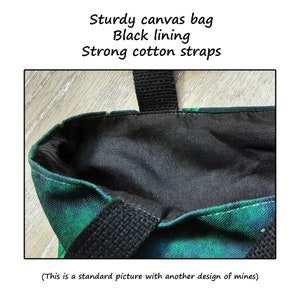 May include: A green and black canvas tote bag with black cotton straps and a black lining. The bag is made of sturdy canvas and has a simple design.