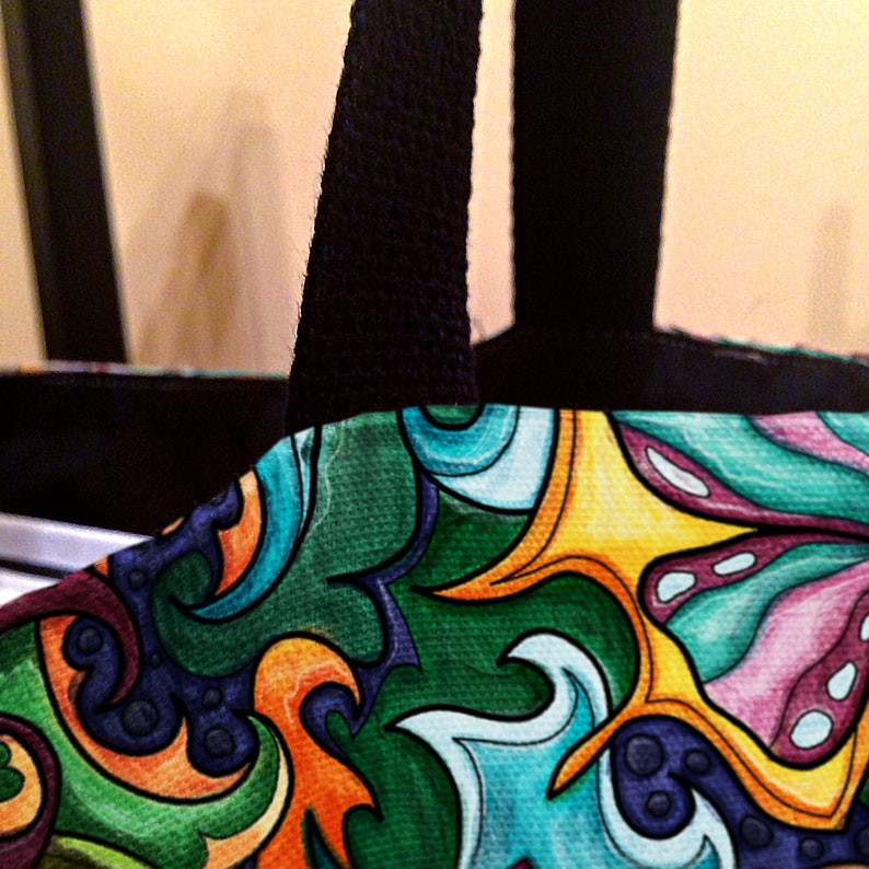 May include: A colorful tote bag with black handles. The bag features a swirling pattern of green, blue, yellow, orange, and pink.