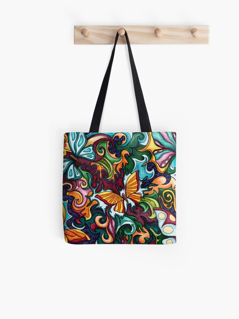 May include: A colorful tote bag with a whimsical design featuring a yellow butterfly surrounded by swirls and abstract shapes in shades of green, blue, orange, red, and purple.