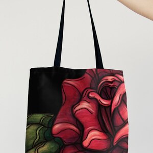 Op de afbeelding: Zwarte tote bag met een rode roos illustratie. De roos is getekend in een gestileerde, bijna cartoonachtige stijl. De roos is het hoofdelement van het ontwerp en neemt het grootste deel van de voorkant van de tas in.