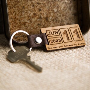 May include: Wooden keychain with a date engraved on it. The date is June 11, 2003. The text "The day you became my Daddy" is also engraved on the keychain.