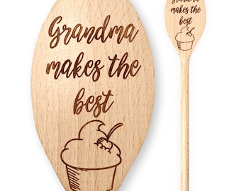 May include: Two wooden spoons with the text "Grandma makes the best" and a cupcake illustration. The spoons are light brown and feature a long handle and an oval-shaped head. The text and cupcake are etched into the wood.