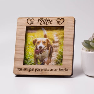 May include: A wooden photo frame with a paw print and heart design. The frame has a photo of a dog inside and the text "You left your paw prints on our hearts".