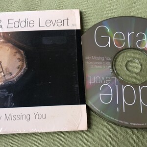 May include: A CD and a CD case with a black and white photo of a clock on the front. The CD case has the text "Gerald & Eddie Levert" and "Already Missing You" on the front. The CD has the text "Gerald Levert" and "Eddie Levert" on the front.