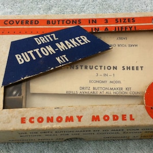 May include: A vintage box for a Dritz Button-Maker Kit, featuring a red, white, and blue color scheme. The box includes instructions and tools for making covered buttons in three sizes: 1 inch, 1 1/2 inches, and 1 1/4 inches. The box also includes 36 buttons. The price is $1.49.