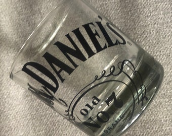 以下が含まれることがあります： 透明なガラス製のショットグラスに、「Jack Daniel's Old No. 7 Brand」という文字が黒で印刷されています。