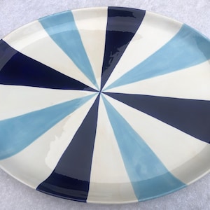 May include: White oval serving platter with a blue and light blue geometric design. The design is a series of radiating triangles that create a sunburst pattern.