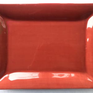 May include: A rectangular ceramic serving dish with a glossy finish. The dish is a vibrant orange color.
