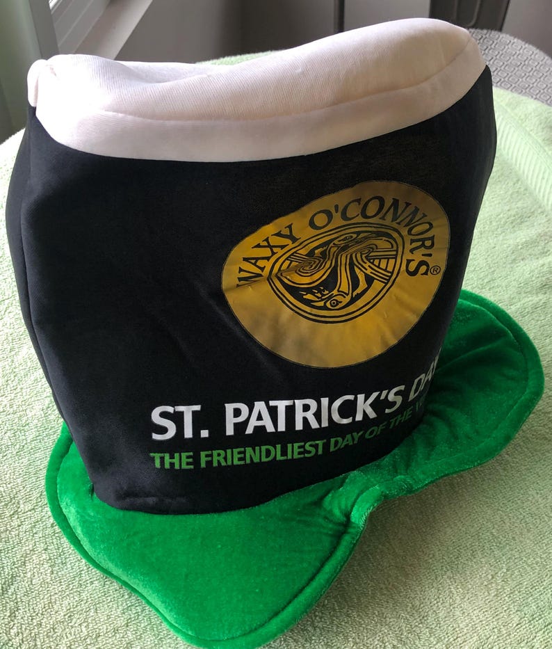 May include: A black and green felt hat shaped like a pint glass with the text "Waxy O'Connor's" and "St. Patrick's Day The Friendliest Day of the Year" printed on it.