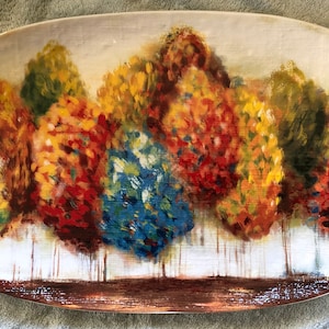May include: A rectangular serving platter with a painted design of a forest scene. The trees are painted in shades of yellow, orange, red, blue, and green. The background is a light beige color.