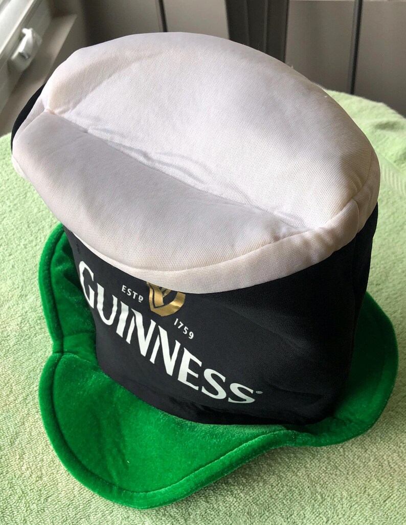 May include: A black and green Guinness hat with a white top and the text "ESTD 1759 GUINNESS" on the front.